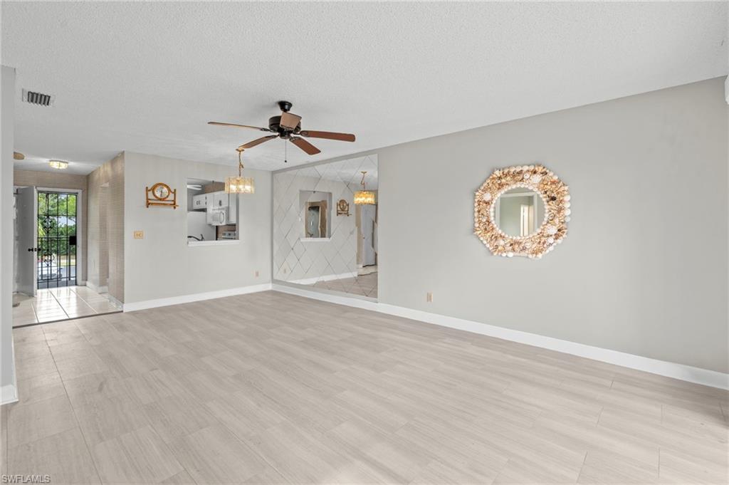 Unfurnished living room featuring a textured ceiling, light wood-style flooring, and ceiling fan