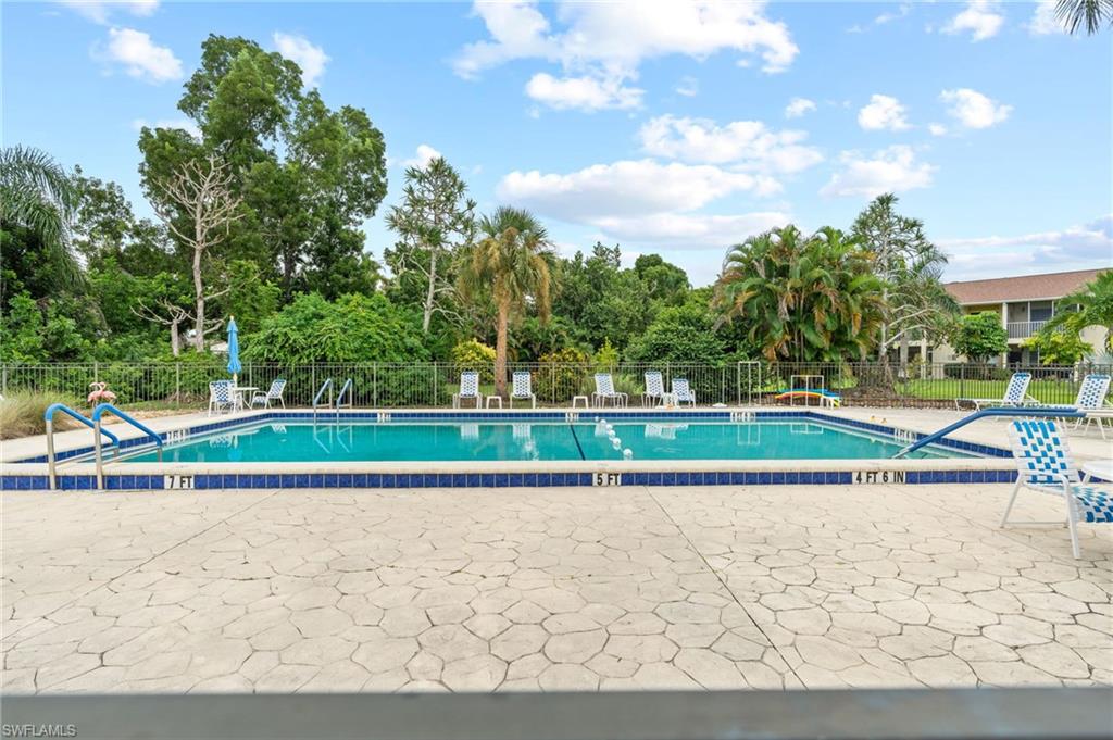 Community pool featuring a patio and view of wooded area