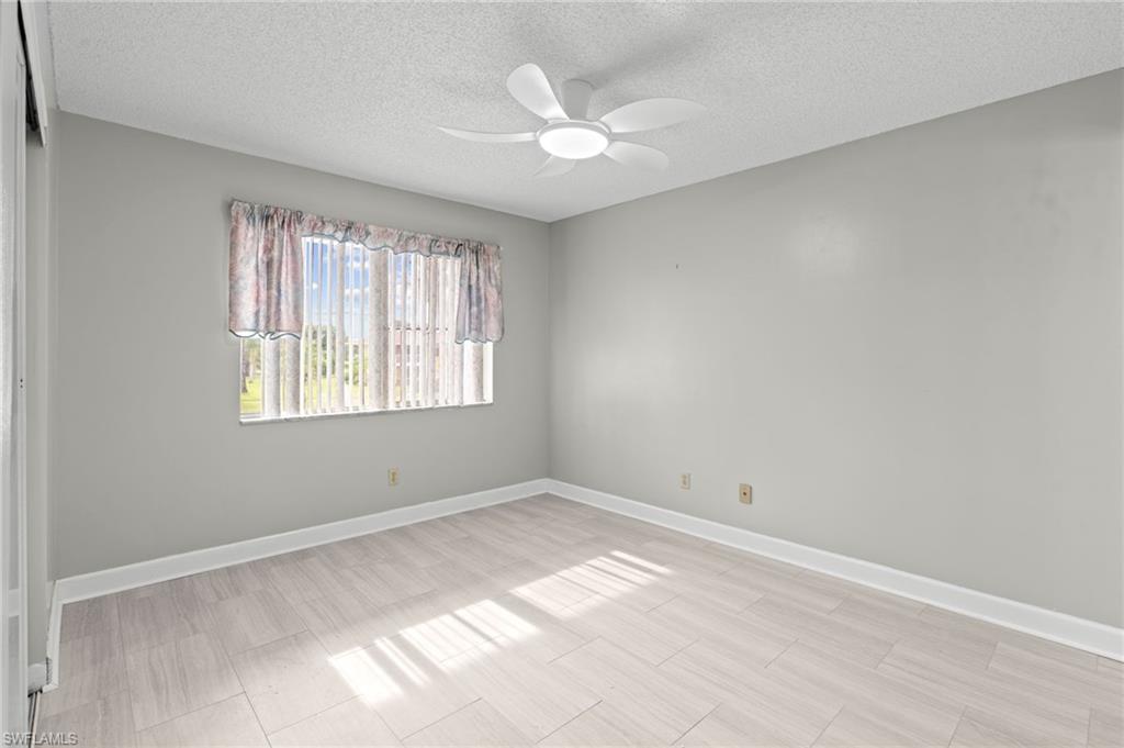 Unfurnished room with a textured ceiling, a ceiling fan, and wood finish floors