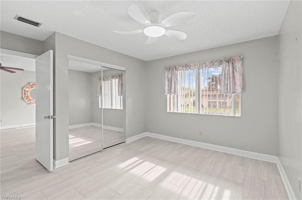 Unfurnished bedroom featuring a closet, ceiling fan, a textured ceiling, and wood finish floors