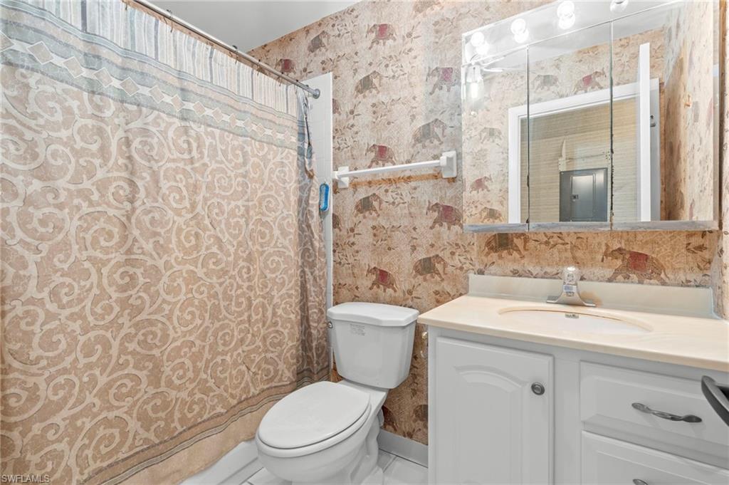 Full bath featuring wallpapered walls, vanity, and tile patterned flooring