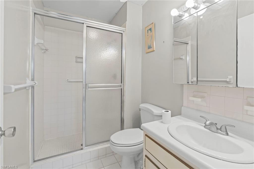 Full bathroom featuring a shower stall, vanity, light tile patterned floors, and backsplash