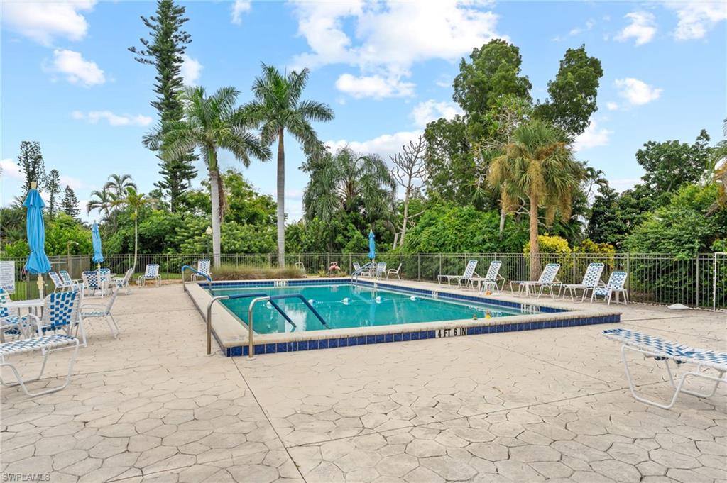 Community pool featuring a patio area and view of wooded area