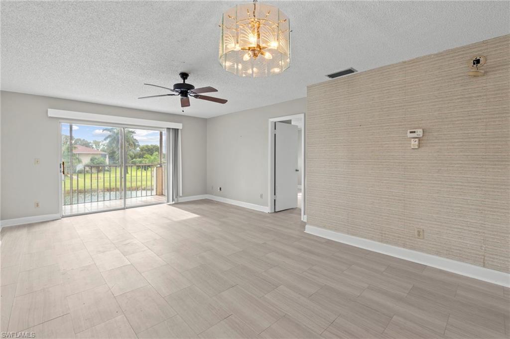 Unfurnished living room with a chandelier, a textured ceiling, light wood-style flooring, and a ceiling fan