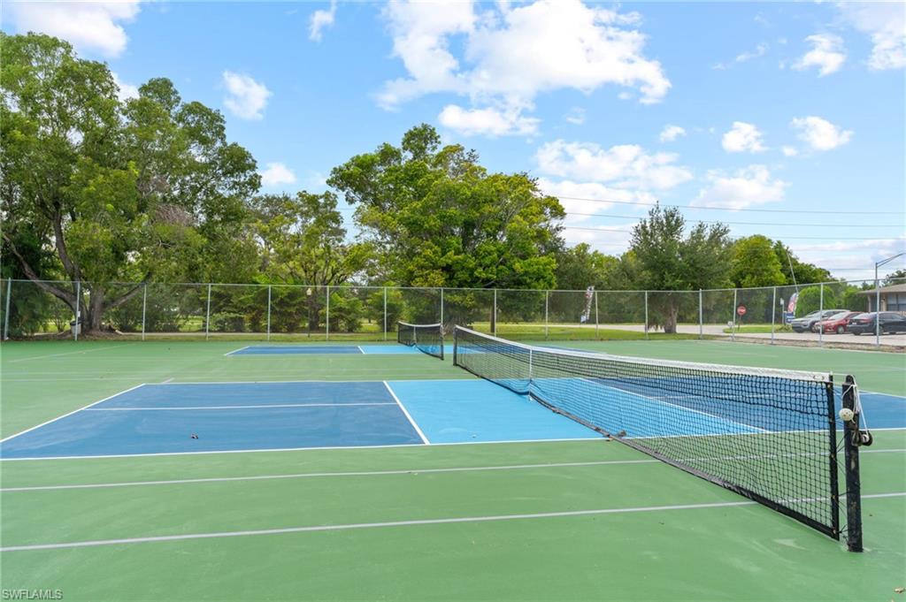 View of tennis court with view of scattered trees