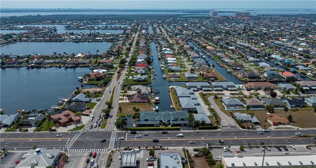 Aerial view of property and surrounding area featuring a nearby body of water and nearby suburban area