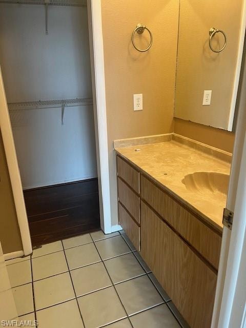 Bathroom with vanity, a walk in closet, and light tile patterned floors