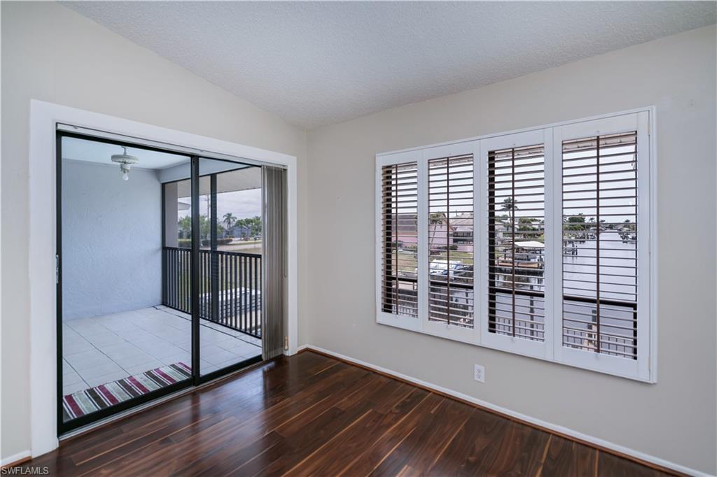 Unfurnished room with dark wood finished floors, a textured ceiling, and vaulted ceiling