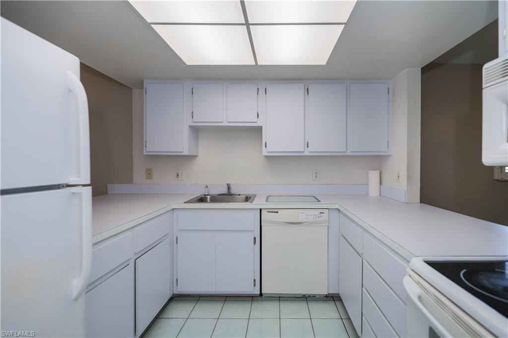 Kitchen with white appliances, white cabinets, light countertops, and light tile patterned floors
