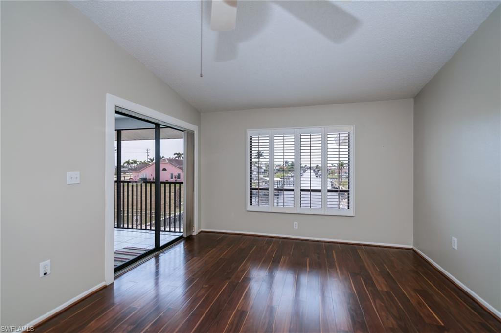 Spare room featuring healthy amount of natural light, dark wood-type flooring, and ceiling fan
