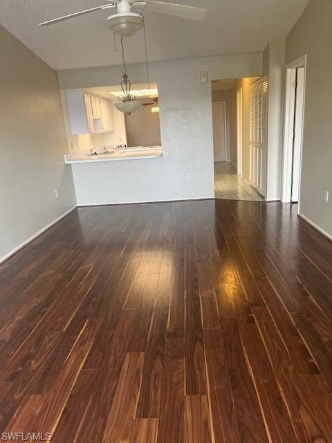 Unfurnished living room with dark wood-style flooring, a textured ceiling, and ceiling fan