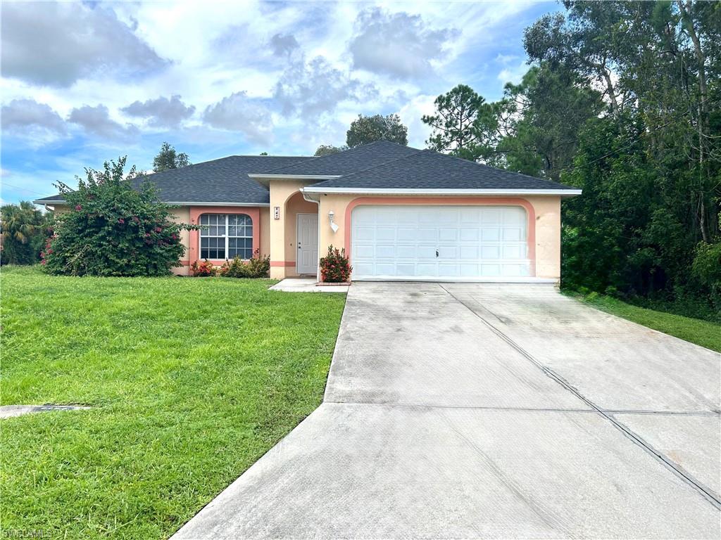 Ranch-style home with stucco siding, driveway, a front yard, an attached garage, and roof with shingles