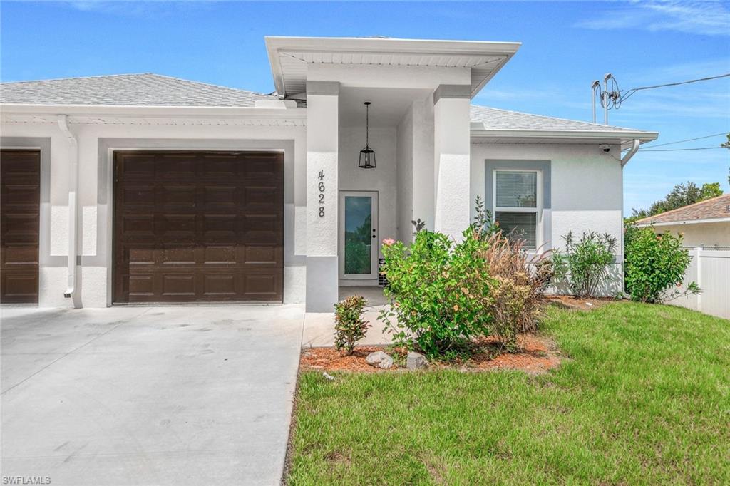 View of front of property featuring driveway, stucco siding, a front yard, a garage, and a porch