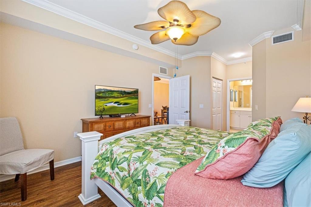 Bedroom featuring crown molding, dark wood finished floors, ensuite bathroom, and ceiling fan