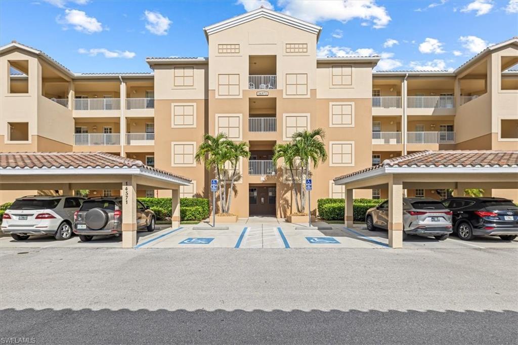 View of apartment building / complex featuring covered parking