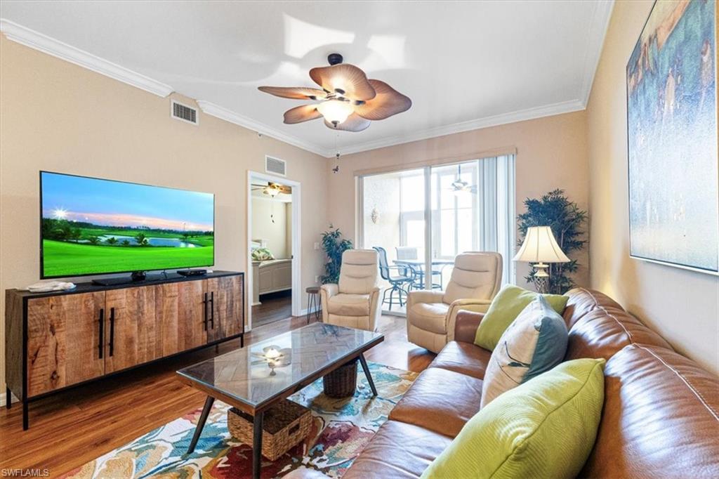 Living room with ornamental molding, wood finished floors, and a ceiling fan