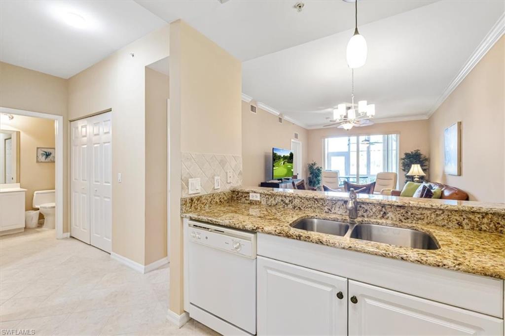 Kitchen featuring open floor plan, white dishwasher, light stone counters, backsplash, and pendant lighting