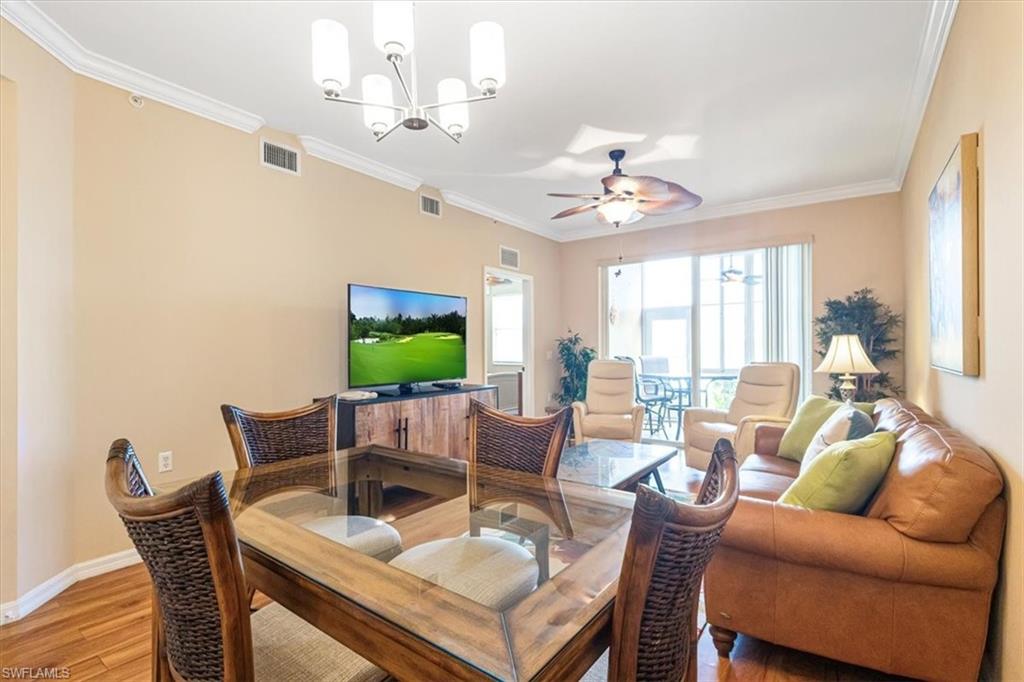 Living room with crown molding, light wood-style floors, ceiling fan, and a chandelier