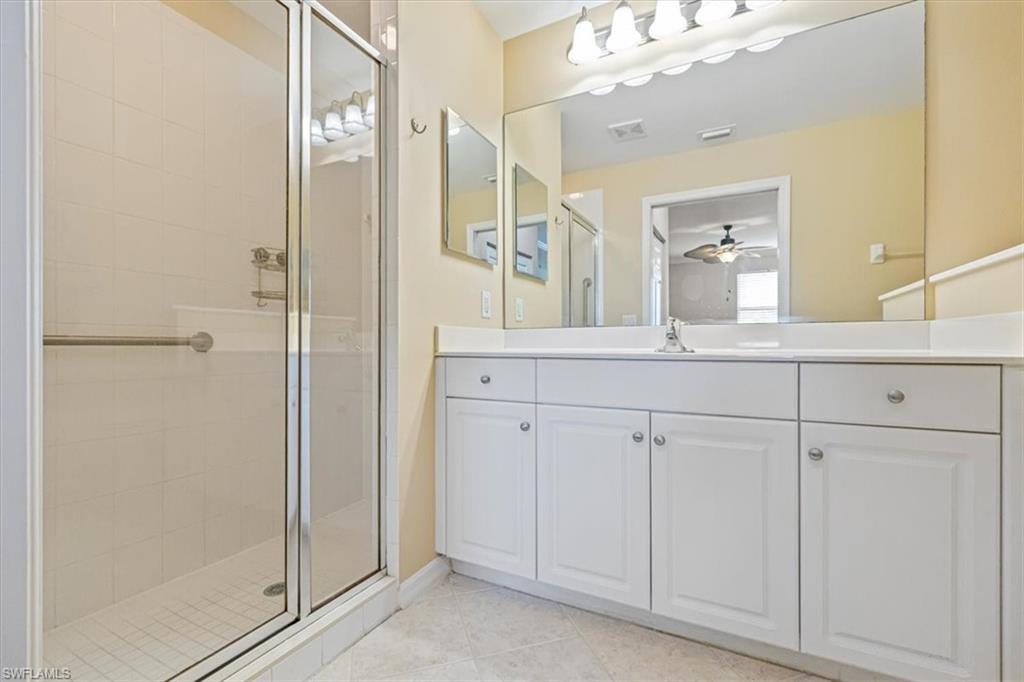 Bathroom featuring a shower stall, vanity, light tile patterned flooring, and a ceiling fan