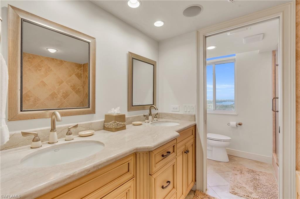 Bathroom with toilet, vanity, and tile patterned floors / virtually enhanced image