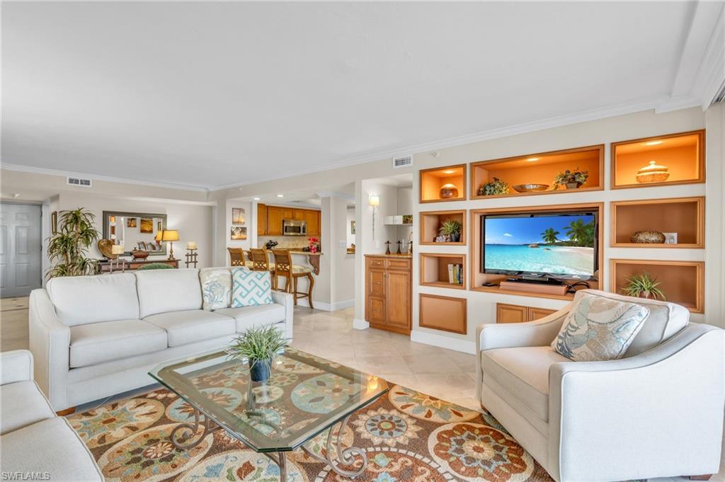 Living room with light tile patterned floors, built in features, and ornamental molding / vrtually enhanced image
