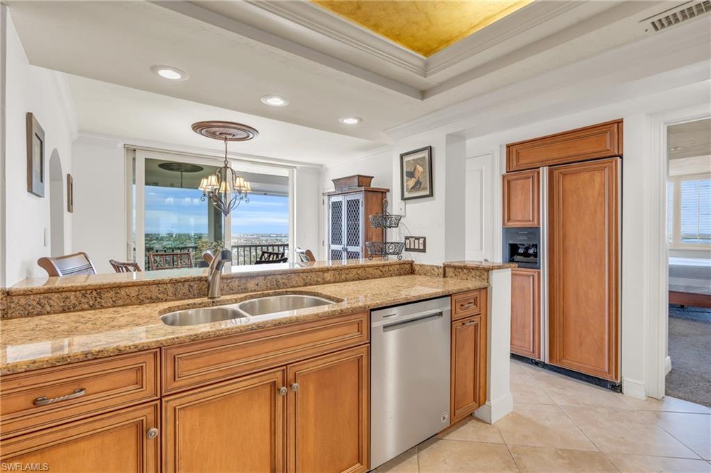 Kitchen with sink, an inviting chandelier, stainless steel dishwasher, pendant lighting, and a tray ceiling / vrtually enhanced image