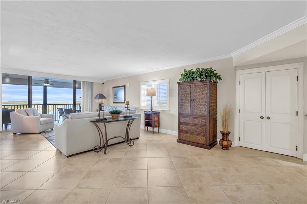 Living room featuring a healthy amount of sunlight, expansive windows, ceiling fan, and crown molding / vrtually enhanced image