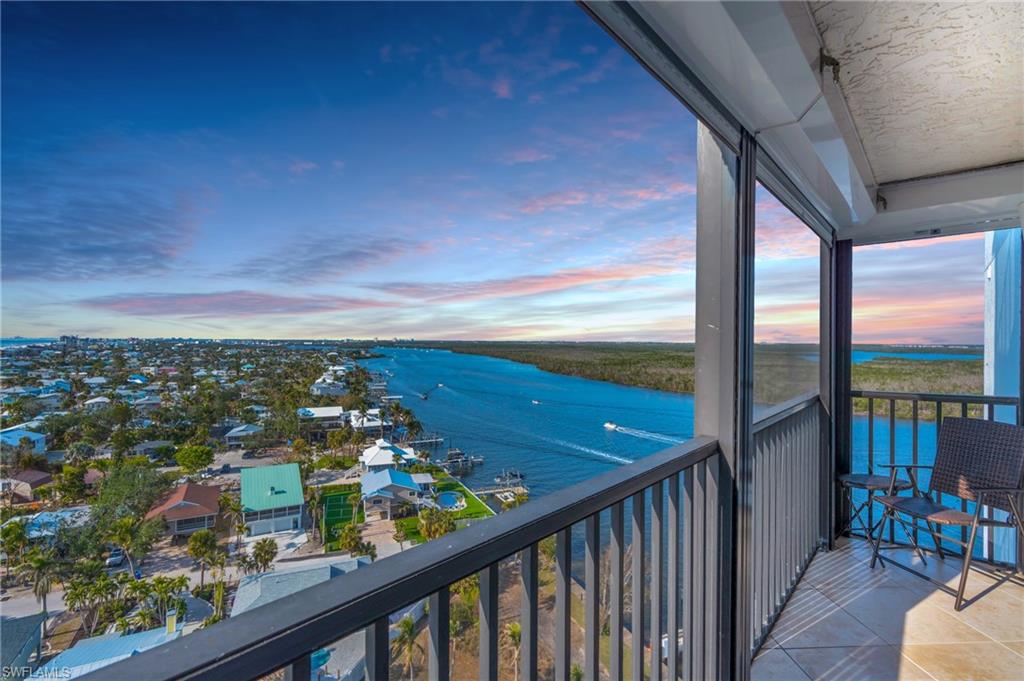 VIRTUALLY ENHANCED - Balcony at dusk featuring a water view