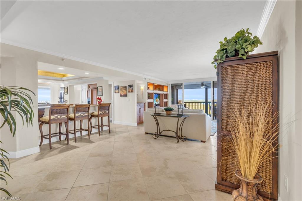 Living room with crown molding, expansive windows, and indoor bar / virtually enhanced image