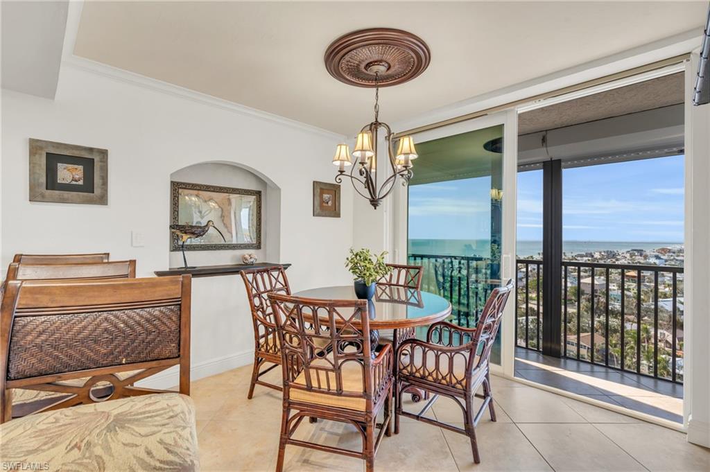 Dining area with crown molding, a water view, a chandelier, and light tile patterned floors / virtually enhanced image