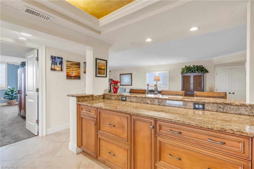 Kitchen featuring plenty of natural light, light stone countertops, and crown molding / virtually enhanced image