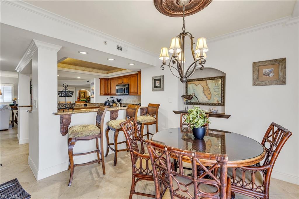 Dining room with light tile patterned floors, a notable chandelier, and ornamental molding / virtually enhanced image