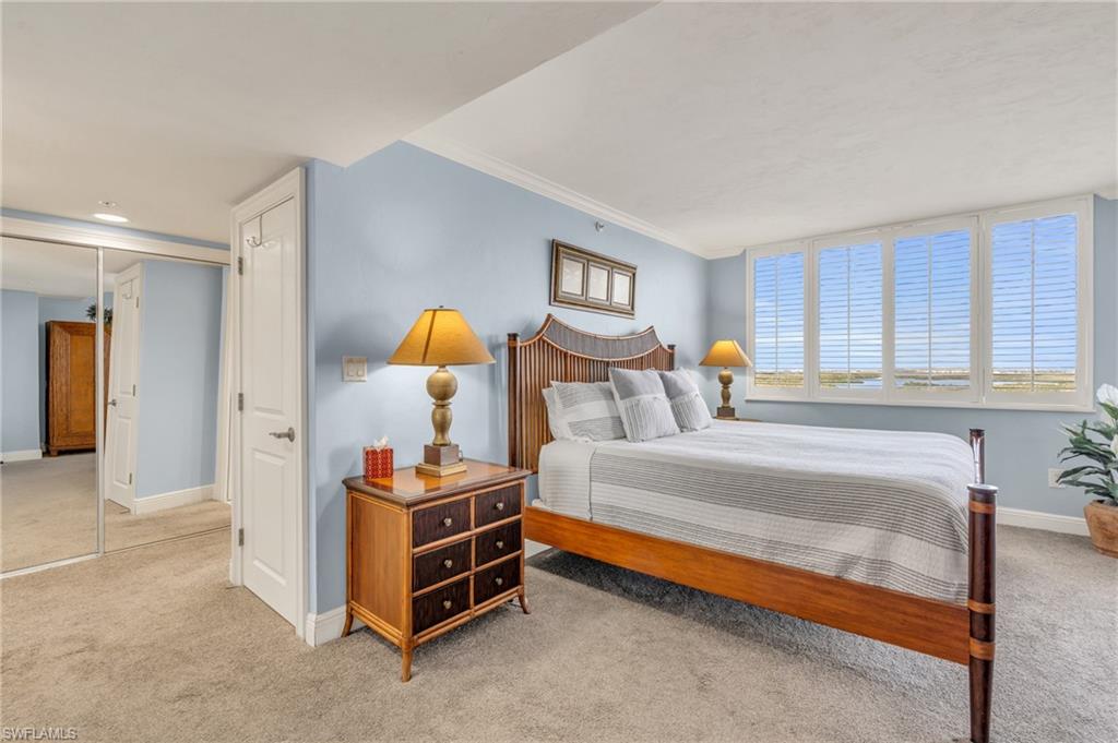 Bedroom with light colored carpet, crown molding, and a closet / virtually enhanced image