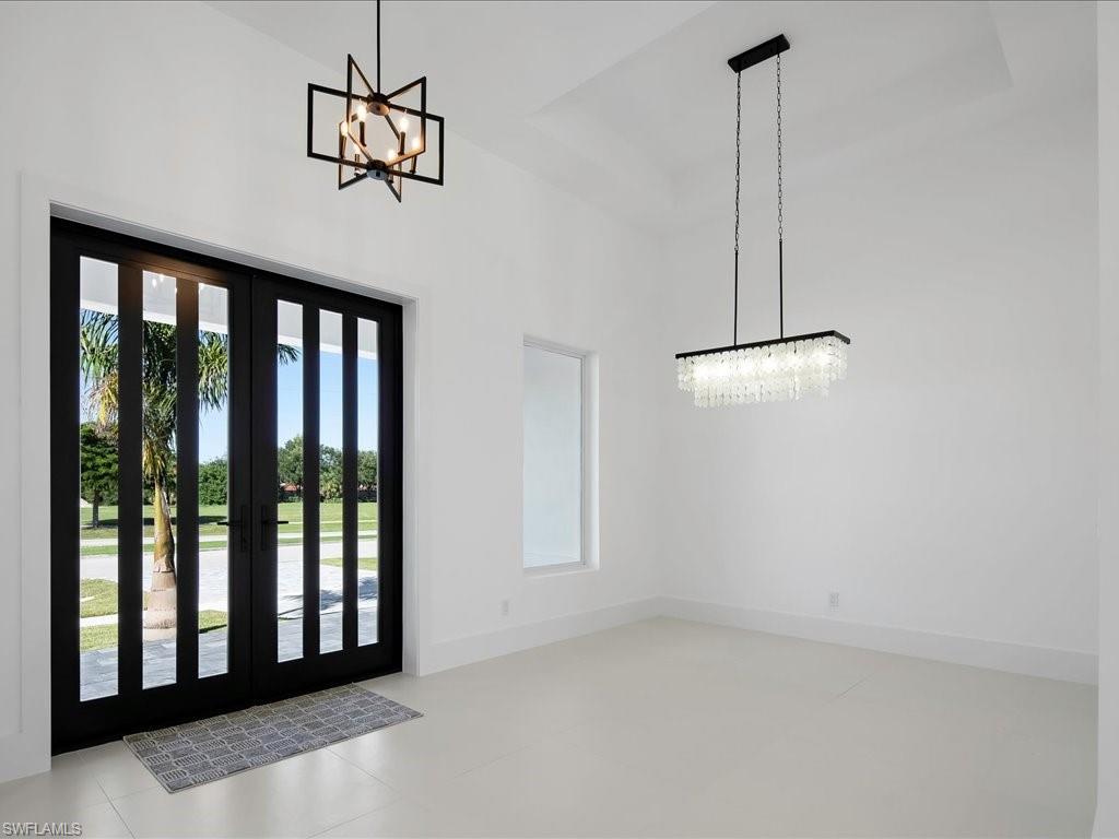 Entrance foyer with a chandelier, a tray ceiling, and light tile patterned floors