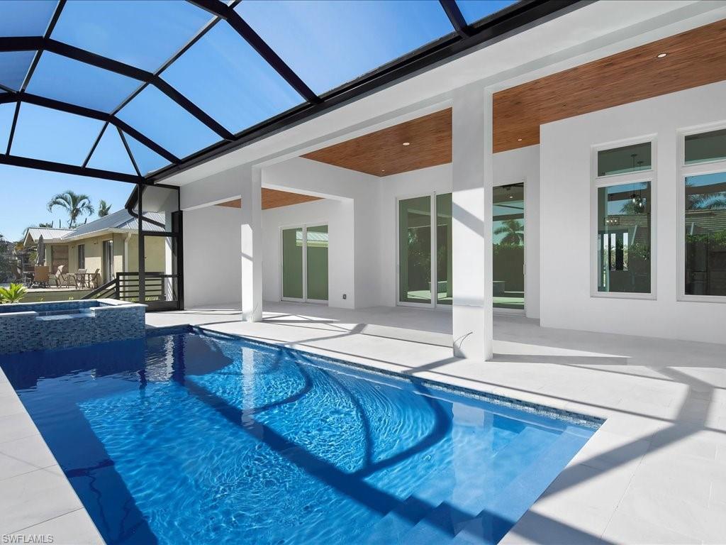 View of pool with a sunroom, a patio, glass enclosure, and a pool with connected hot tub