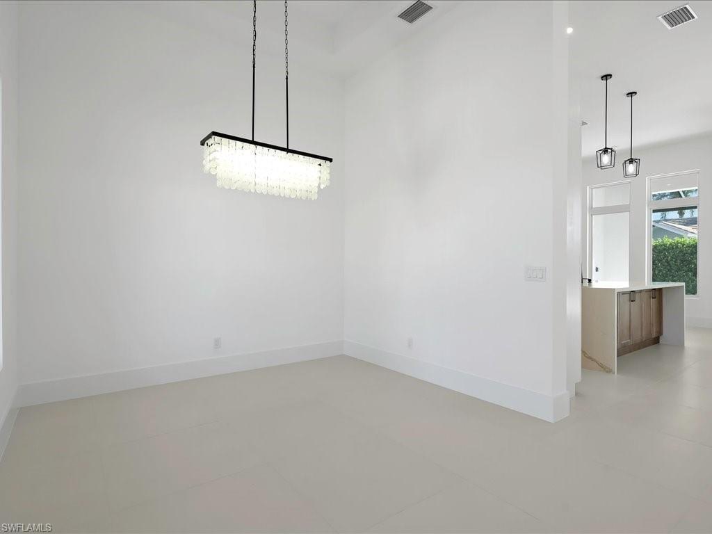 Unfurnished dining area with baseboards and a high ceiling