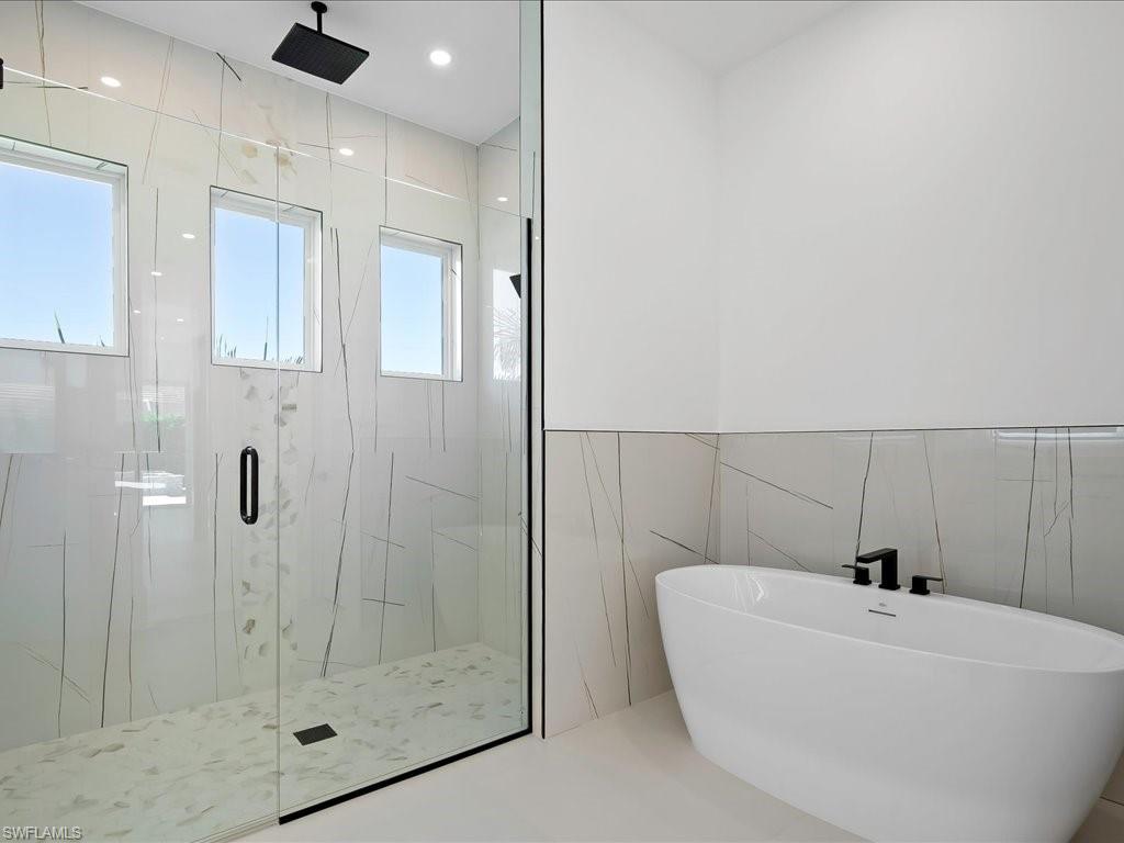 Full bathroom with tile walls, a freestanding bath, a marble finish shower, and recessed lighting