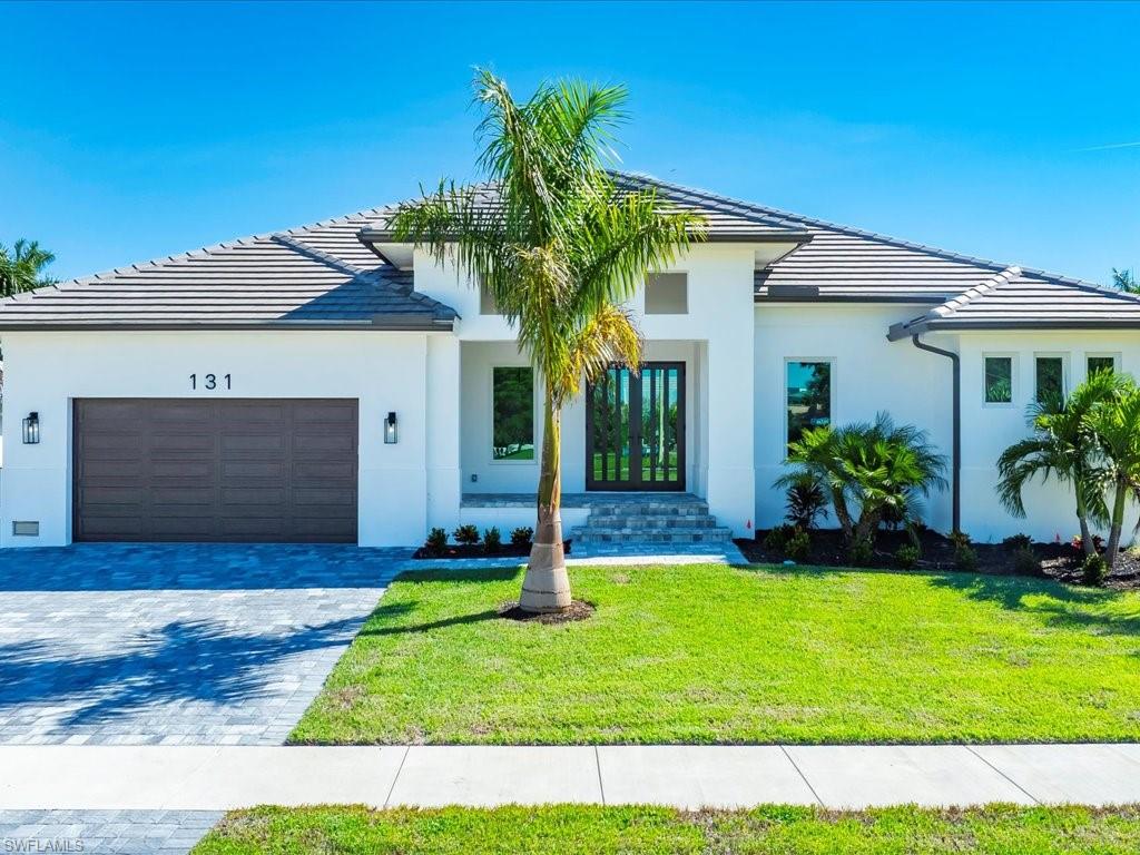 View of front of house featuring a front lawn, decorative driveway, a tiled roof, and a garage