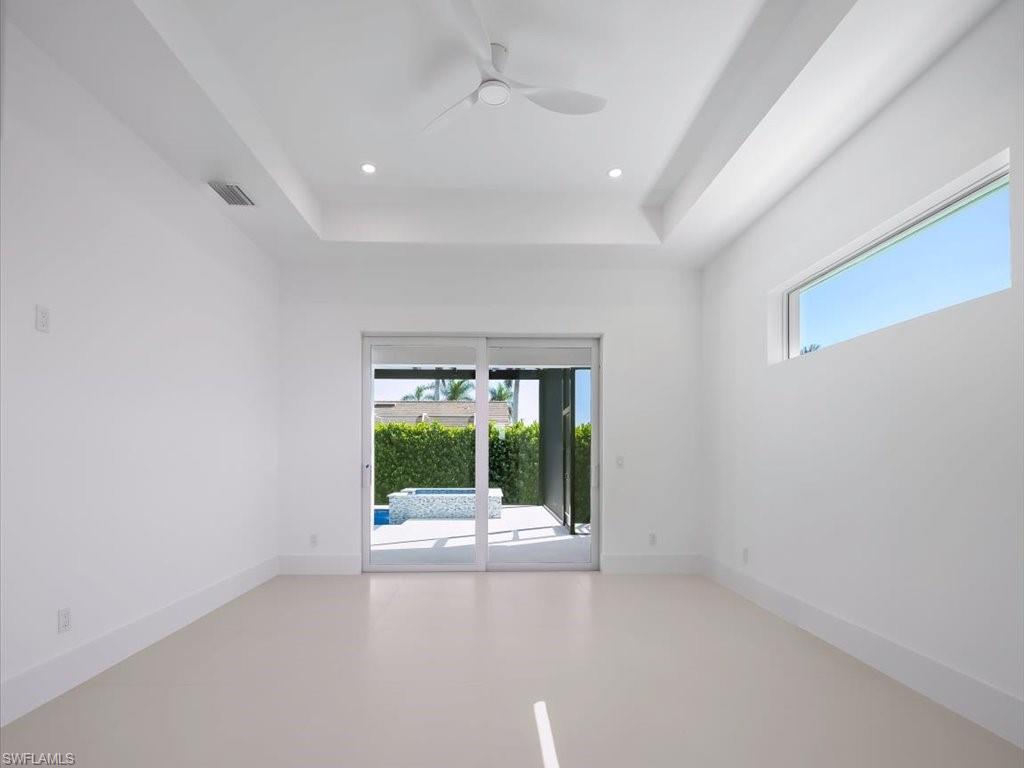 Empty room with a tray ceiling, ceiling fan, and recessed lighting