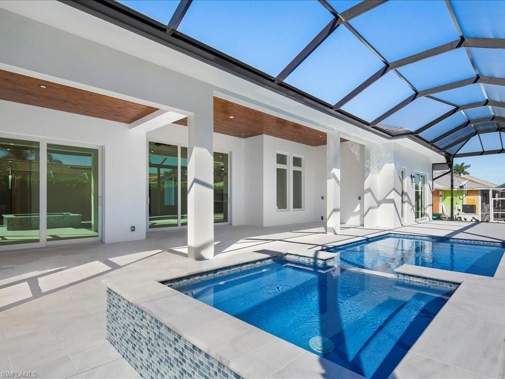 View of swimming pool with a sunroom, a lanai, a pool with connected hot tub, and a patio area