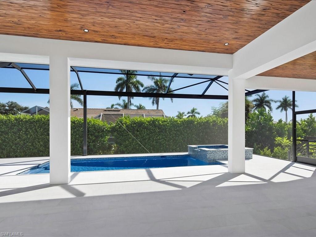 View of swimming pool featuring a sunroom, a pool with connected hot tub, a lanai, and a patio