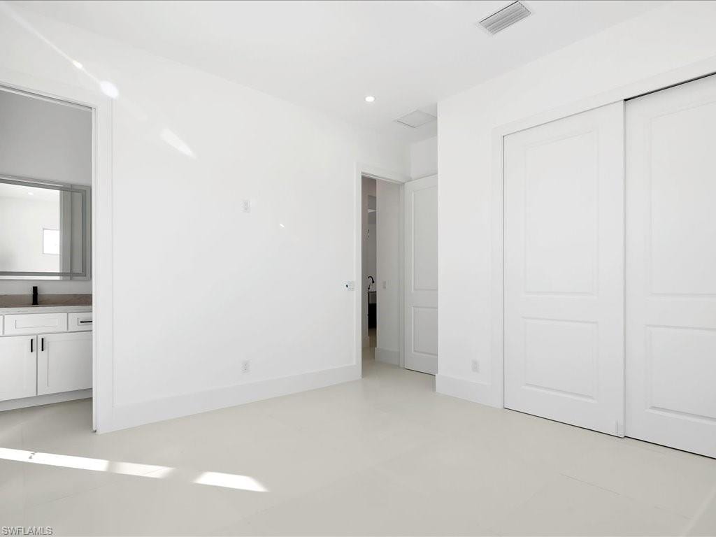 Unfurnished bedroom with ensuite bathroom, recessed lighting, and a closet