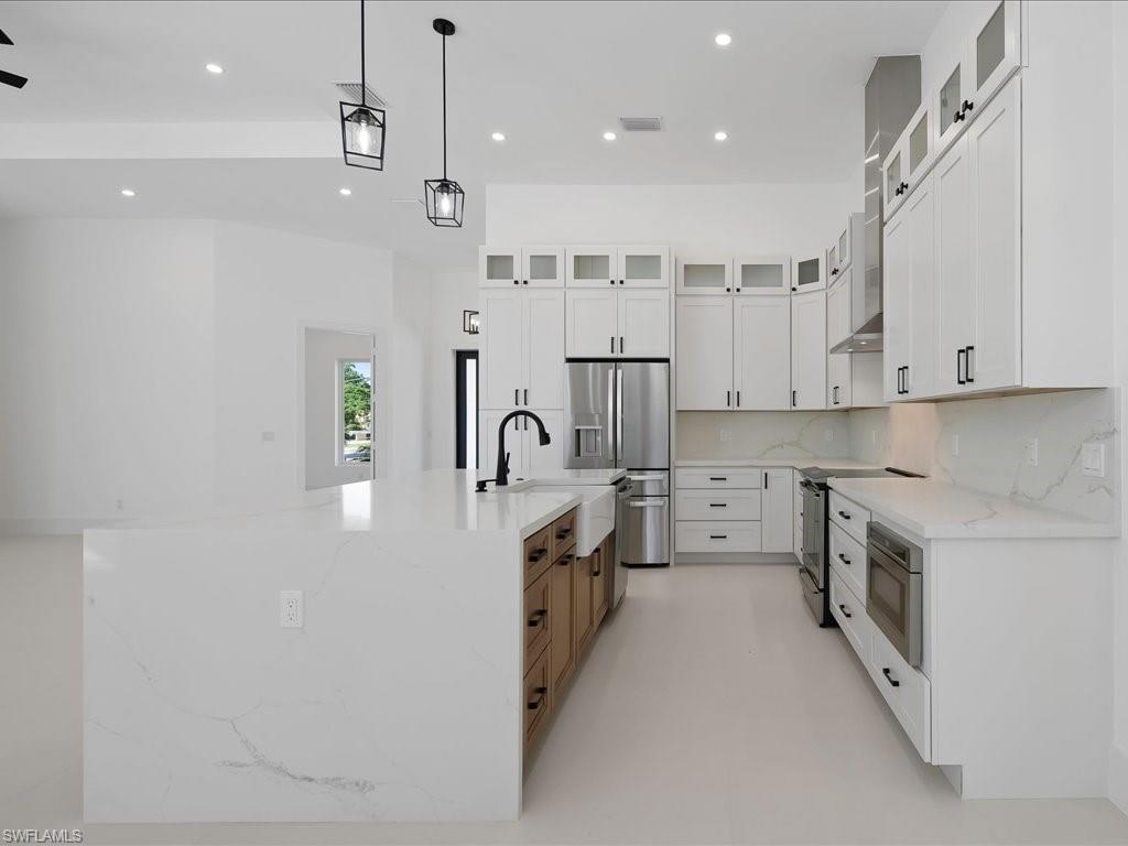 Kitchen featuring glass insert cabinets, light stone counters, white cabinets, recessed lighting, and appliances with stainless steel finishes