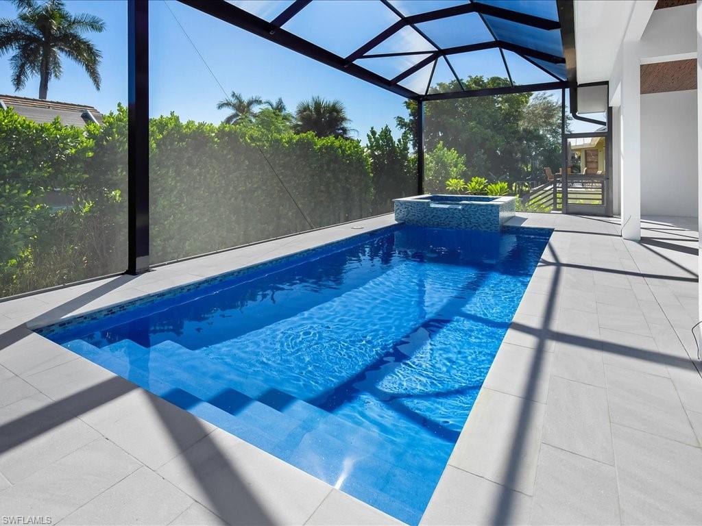 View of pool featuring glass enclosure, a patio area, a sunroom, and a pool with connected hot tub