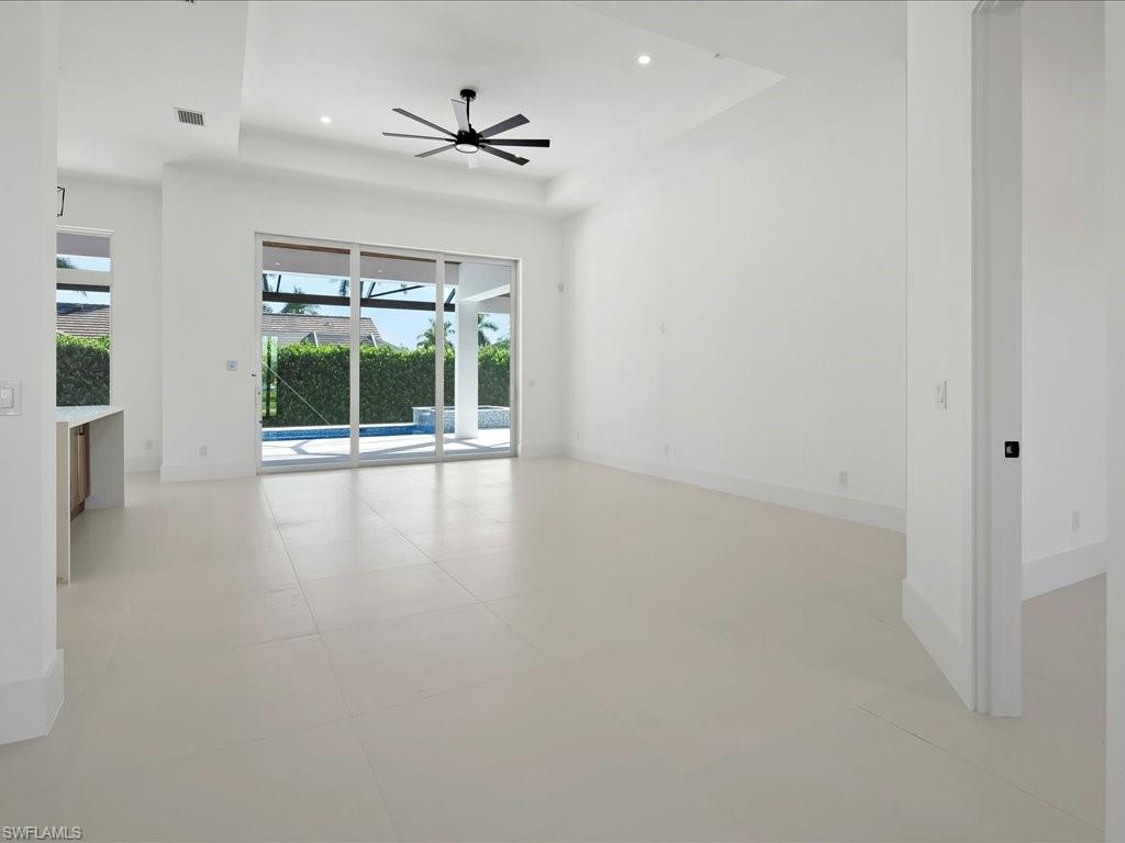 Empty room featuring a tray ceiling, recessed lighting, a ceiling fan, and a sunroom