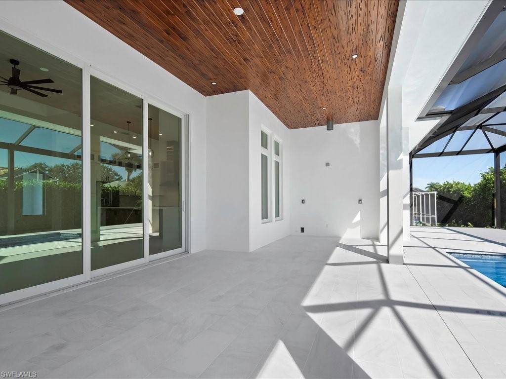 View of patio with a sunroom, glass enclosure, ceiling fan, and an outdoor pool