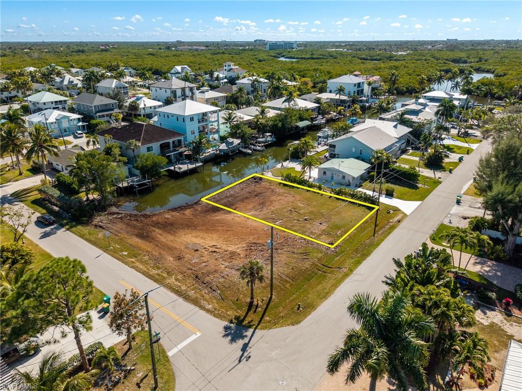 Aerial perspective of suburban area with property parcel outlined and a nearby body of water