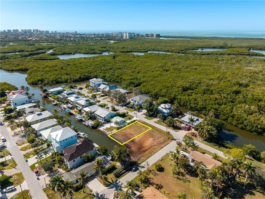 Aerial overview of property's location featuring a nearby body of water, property parcel outlined, and nearby suburban area