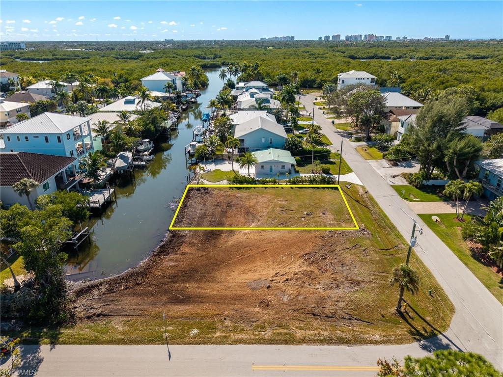 Aerial view of residential area with property boundaries highlighted and a nearby body of water