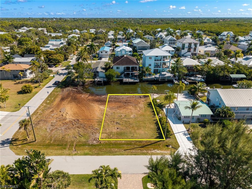 Aerial view of residential area with property boundaries highlighted and a large body of water